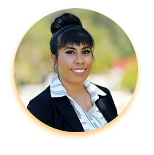 Rebecca Esparza, a twenty-something Latina with long straight black hair worn in a thick bun, smiles for a professional headshot. She has straight white teeth and wears a white collared shirt and black blazer.