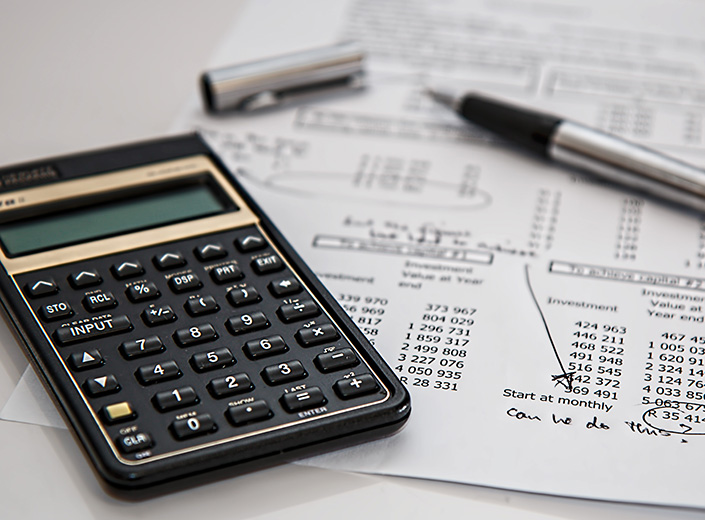 Accounting paperwork with a pen and calculator on top of it.