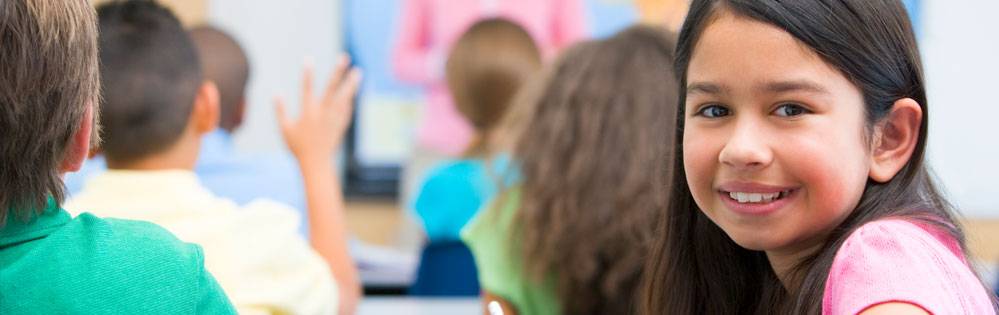 child looking back at camera while sitting at desk