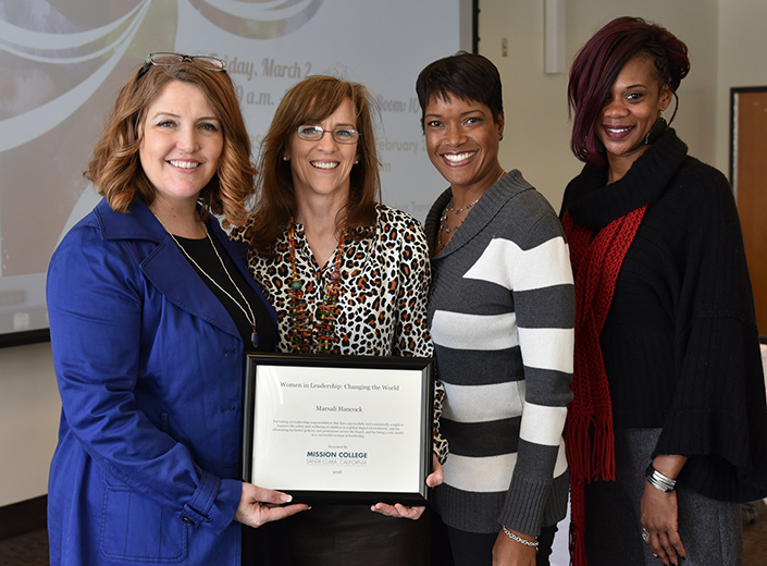 Women in Leadership summit. Four women pose with a framed award. 