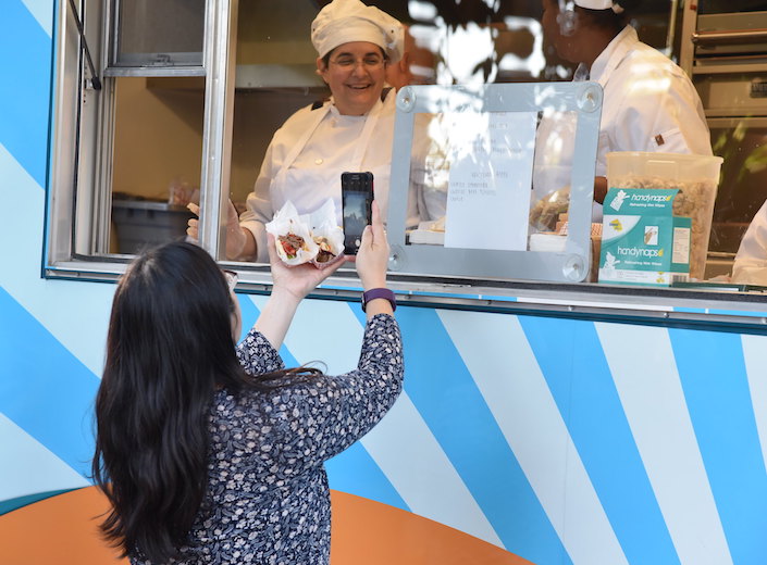 Student chef serves a woman with long dark hair.