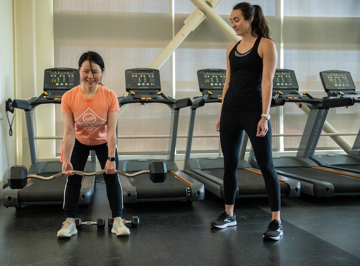 Kaitlin Ferguson instructing a female student in weight lifting techniques.