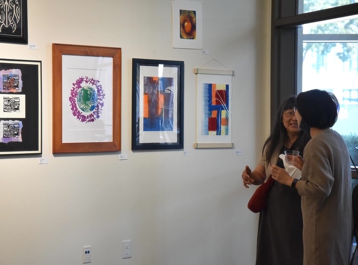 Two women look at impressionist paintings in the Vargas Gallery of Mission College.