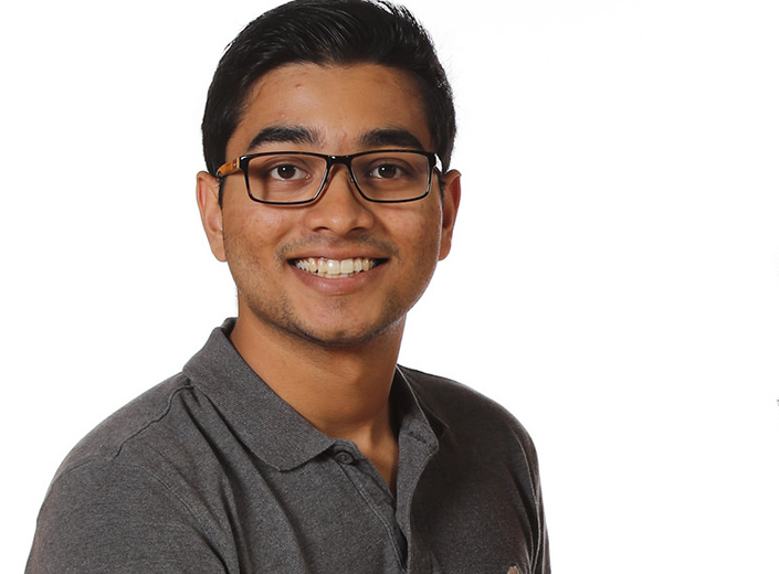 Male student with black plastic glasses, dark hair, and brown skin.