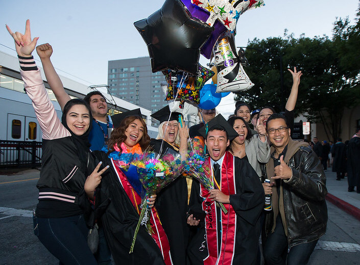 Happy graduates in a group outside posing for a photo.