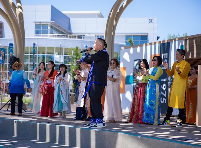 Asian female student drums on djembe hand drum held by Dr. Piper during International Day celebration.