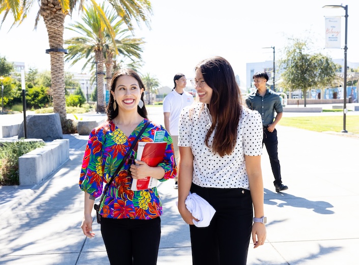 Welcome Center Ambassadors walk together. In the front of the group are two young women, both with dark hair. One has a bright floral shirt.